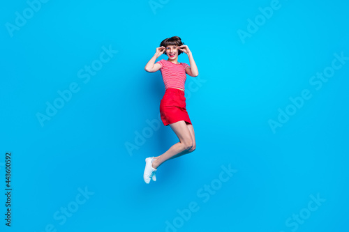 Full length body size photo girl jumping up careless smiling happy cheerful isolated vibrant blue color background