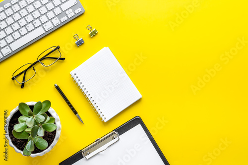 Office desk table with equipment - computer keyboard and notepad, top view