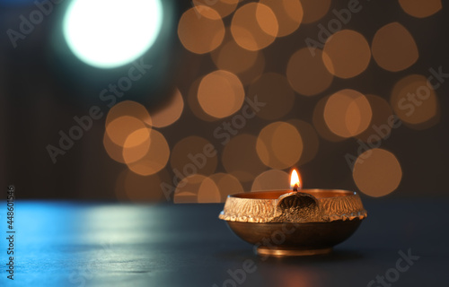 Lit diya lamp on dark table, space for text. Diwali celebration photo