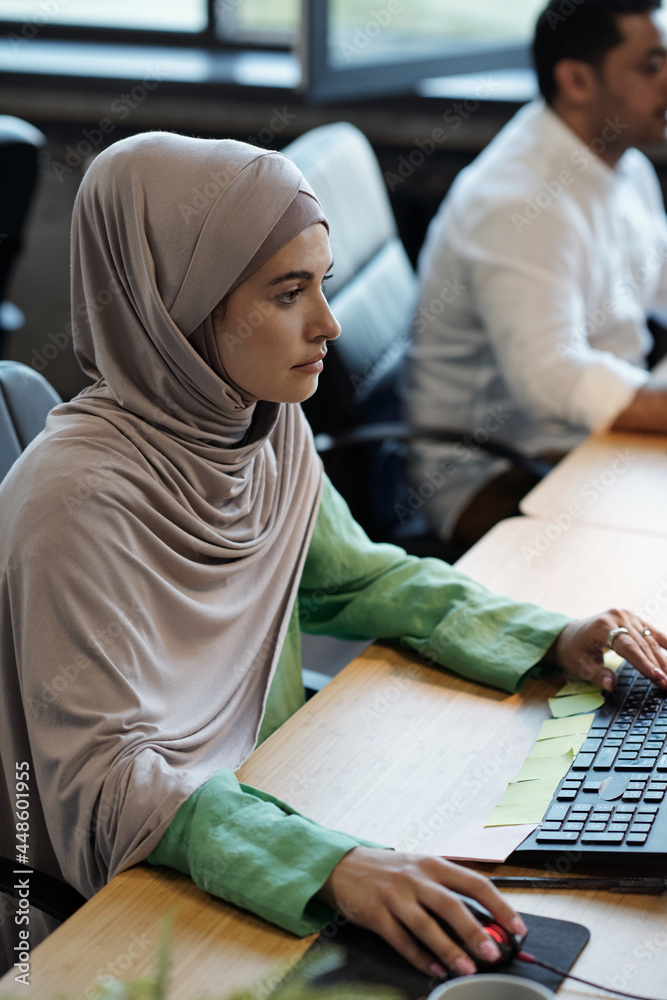 Pretty Muslim businesswoman in hijab sitting in front of computer during work Pretty Muslim businesswoman in hijab sitting in front of computer during work
