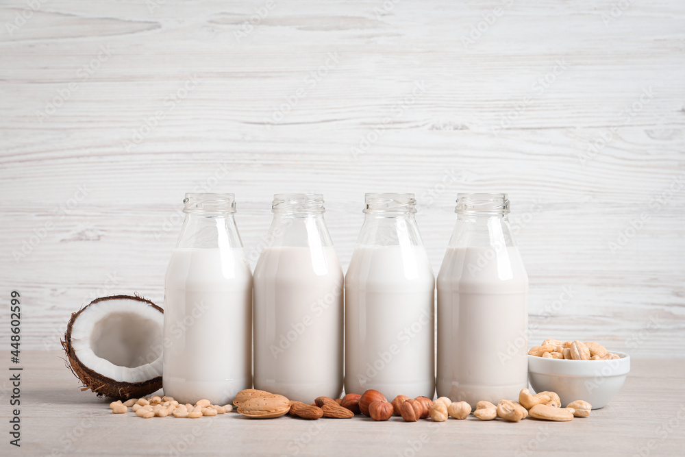Different nut milks in glass bottles on white table Different nut milks in glass bottles on white table