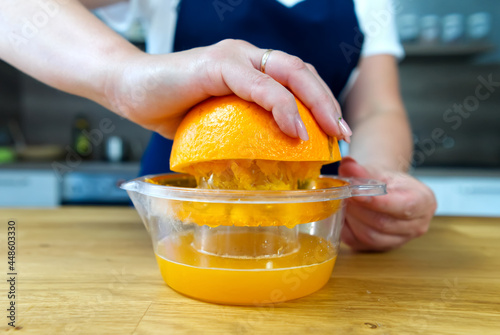 Hand squeezing orange juice. Close up fresh drink making process at home