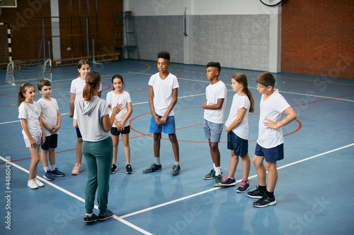 Multi-ethnic group of school children having PE class with female coach.