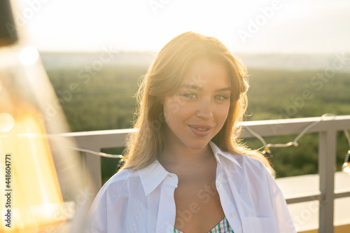 Cute young blond female in white shirt enjoying rooftop party