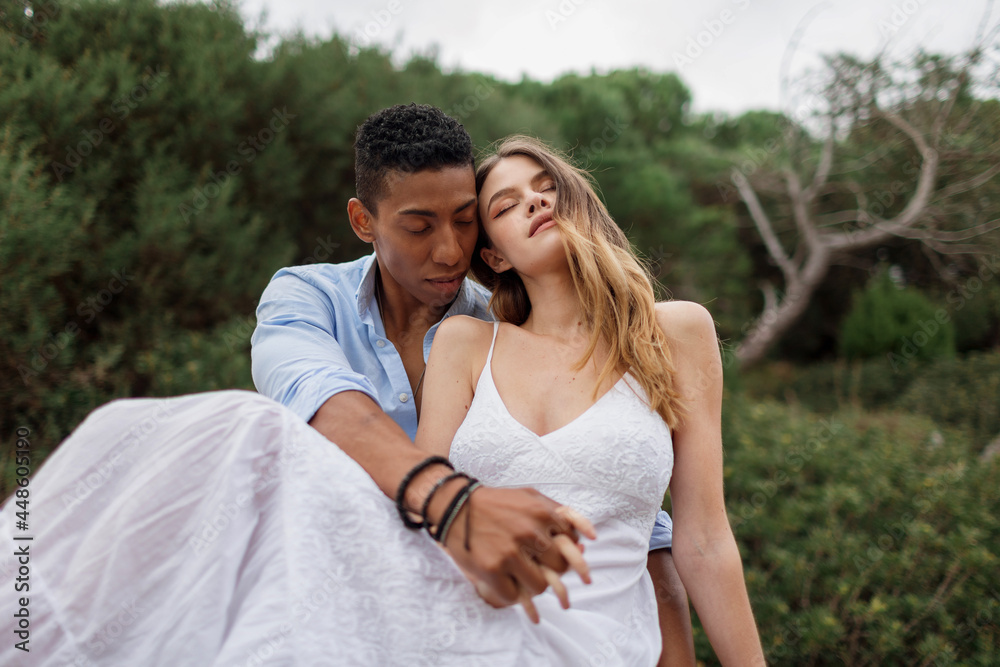 Loving multiethnic newlywed couple embracing in forest Loving multiethnic newlywed couple embracing in forest