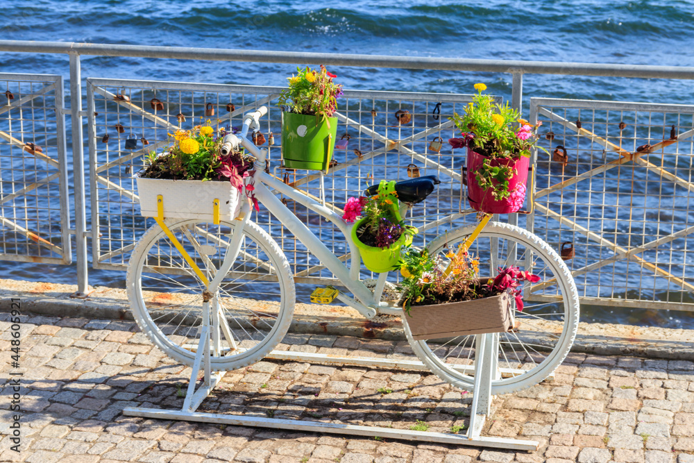 Decorative bicycle shape stand for plants and flowers on the embankment by a sea