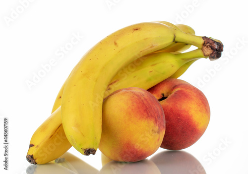 Several ripe bananas and peaches, close-up, isolated on white.