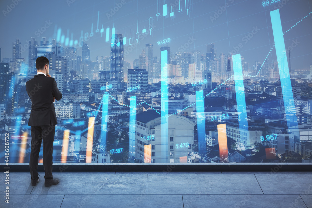 Back view of thoughtful young businessman looking at night city view with forex chart. Trade, oil price and market concept. Double exposure.