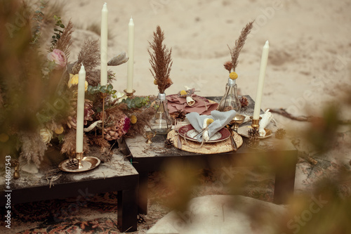 A table  designed for a boho style event with an eucalyptus, vintage plates and other rustic touches. On seaside in the sand dunes