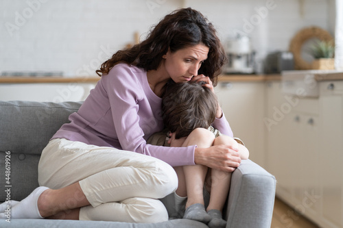Small boy receiving love, protection and support from loving mom cuddling little son offended child cry on sofa. Caring mother consoling kid with tender embraces. Worried parent hug upset preschooler