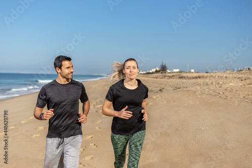 A fitness trainer and a client, a European woman, shake hands. Happy and contented. Against the background of the sea in summer. © sergojpg