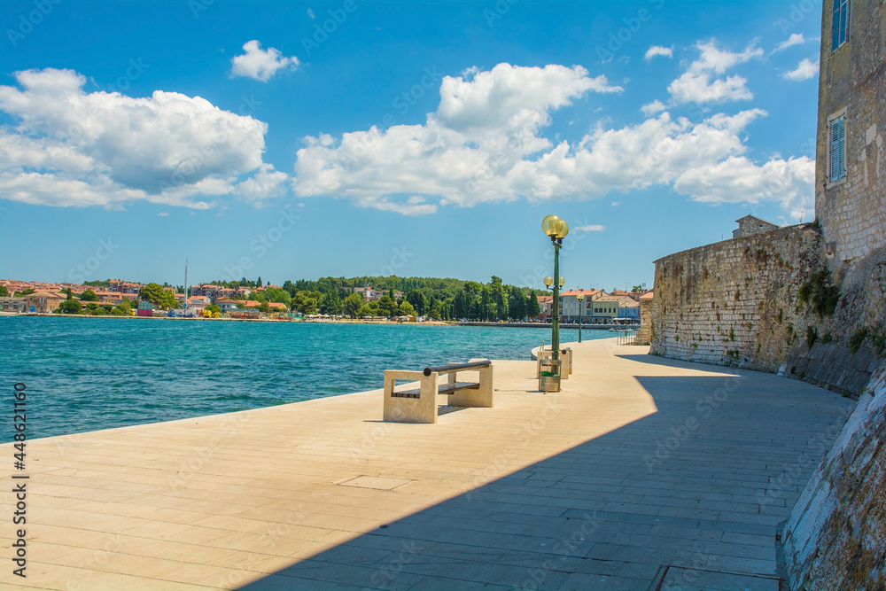 Obraz premium Part of the old defensive walls of the historic medieval coastal town of Porec in Istria, Croatia. The coast to the north of the town centre can be seen on the opposite shore 