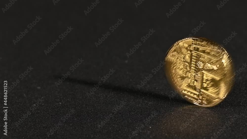 Golden bitcoin physical coin spinning over black Golden bitcoin physical coin spinning over black