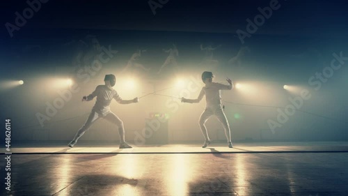 Footage of two fencing athletes duel . Two Professional Fencers Show Masterful Swordsmanship in their Foil Fight. Fencing training . Shot on ARRI ALEXA camera . 