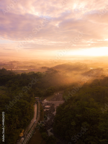 Fototapeta Naklejka Na Ścianę i Meble -  Drone photo of the Indonesian rural landscape with river and forest in the morning on foggy weather