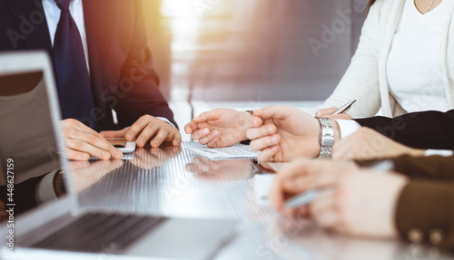 Business people discussing contract while working together in sunny modern office. Unknown businessman and woman with colleagues or lawyers at meeting