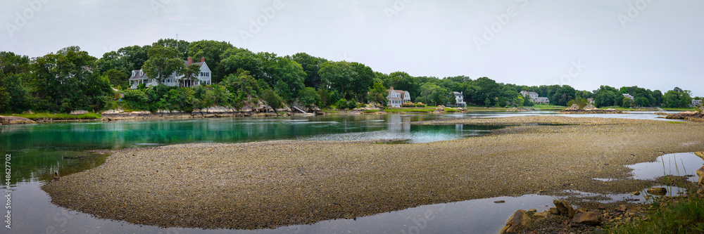 A panoramic river landscape with gravel sandbar, wooded hills, and crystal clear turquoise colored water in North River, Massachusetts.