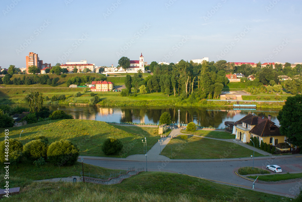 Grodno, Belarus. Embankment of the Neman River in the early morning. Town houses and a Catholic church reflecting in the water.