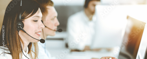 Asian woman working at customer service office. Business concept. Group of diverse operators at work in sunny call center.