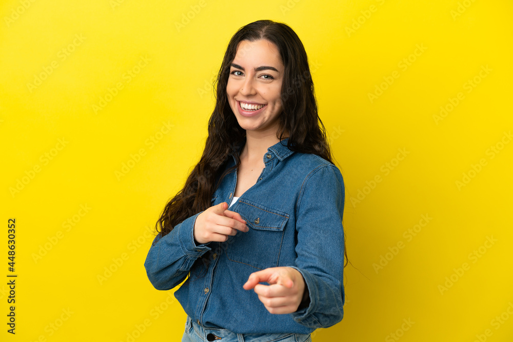 Young caucasian woman isolated on yellow background surprised and pointing front Young caucasian woman isolated on yellow background surprised and pointing front