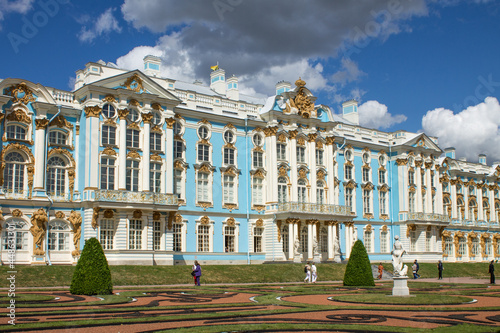 St. Petersburg, Russia, July, 21, 2021: the facade of the Catherine Palace with geometric flower beds in Tsarskoye Selo on a sunny summer day against a blue cloudy sky