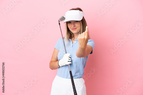 Young golfer player woman isolated on pink background doing coming gesture © luismolinero