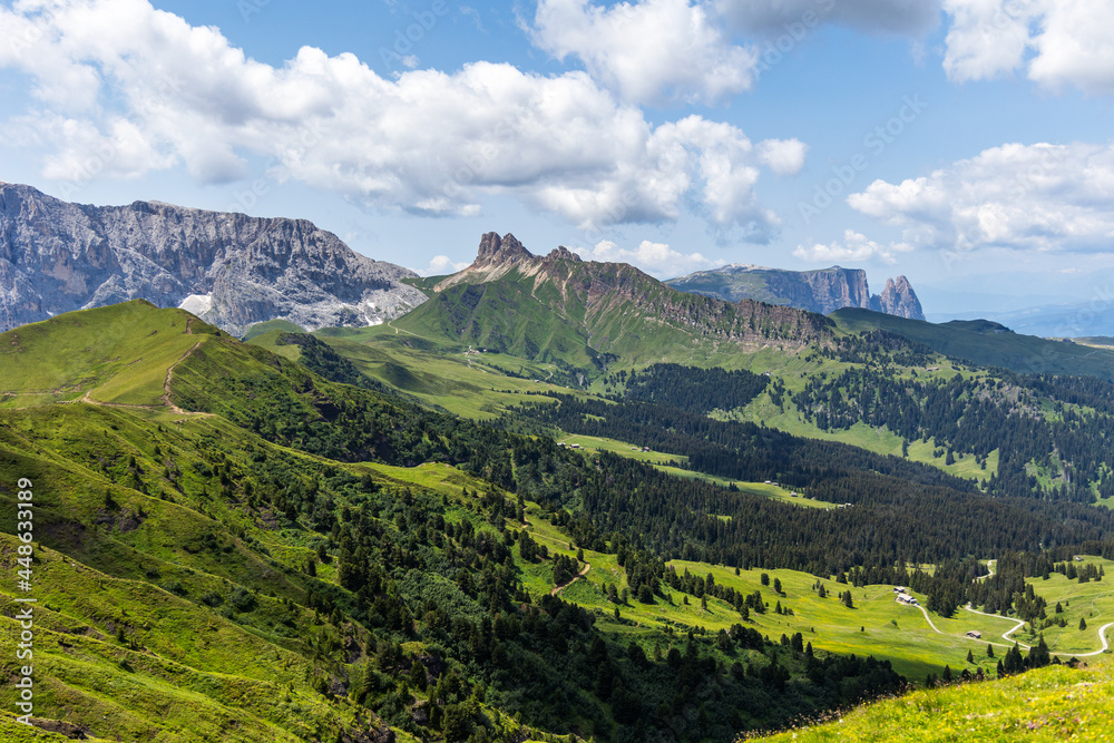 Jagged mountain ranges rising over the lush green fields of grass in the Dolomite mountains
