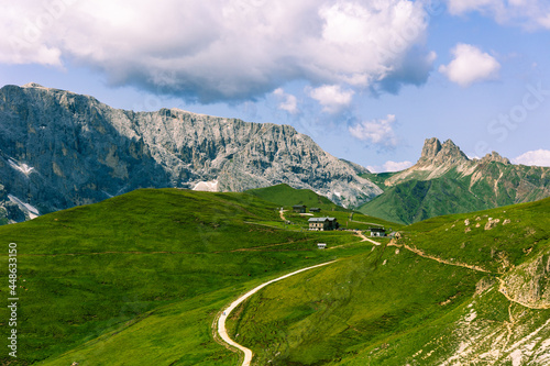 Alpine huts located between the mountains on lush green fields of grass in the Dolomite mountains © Tom