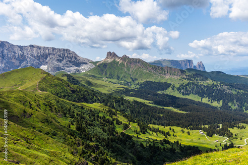 Jagged mountain ranges rising over the lush green fields of grass in the Dolomite mountains