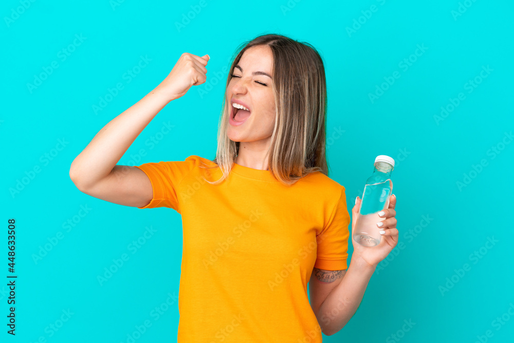 Young Romanian woman with a bottle of water isolated on blue background celebrating a victory Young Romanian woman with a bottle of water isolated on blue background celebrating a victory