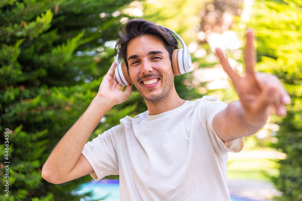 Obraz premium Young caucasian man in a park listening music and singing