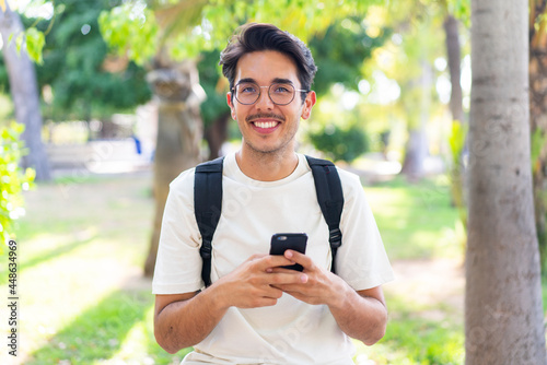 Young student man at outdoors using mobile phone