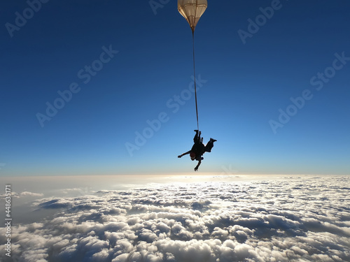 Tandem jump with an amazing sun at the background and clouds