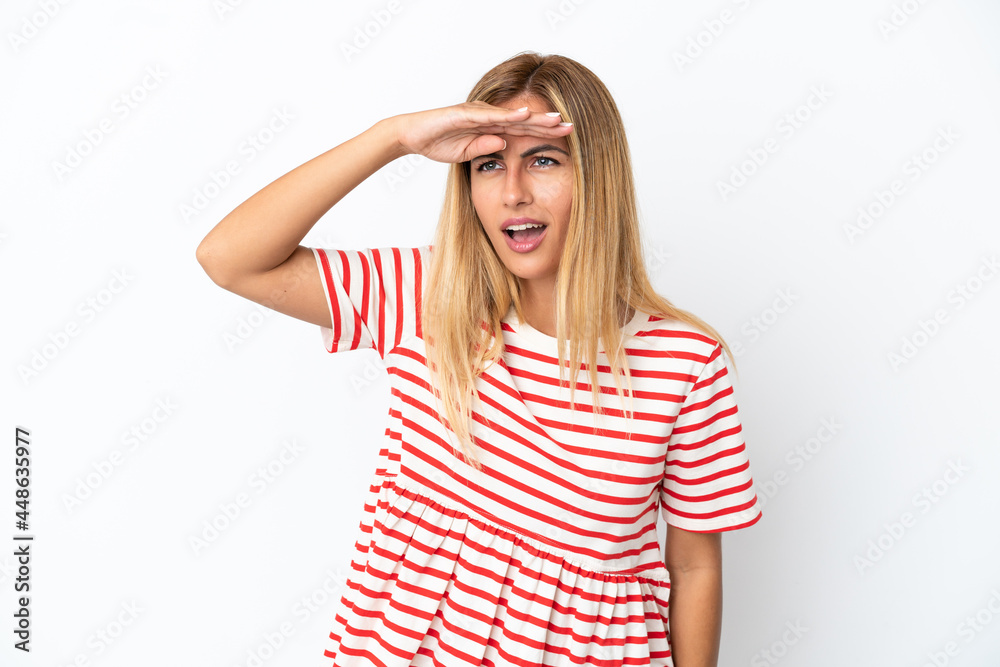 Blonde Uruguayan girl isolated on white background looking far away with hand to look something Blonde Uruguayan girl isolated on white background looking far away with hand to look something