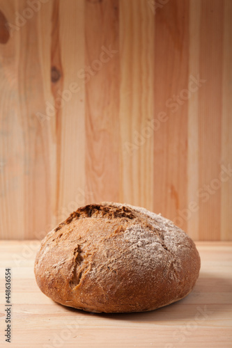 Handmade fresh wheat bread on wooden background in the morning light. vertical frame side view with space area for text or design