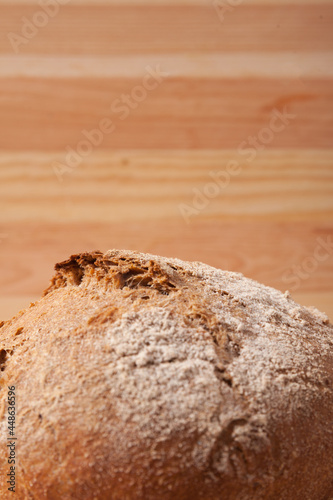 Handmade fresh wheat bread on wooden background in the morning light. vertical close-up frame side view with space area for text or design.