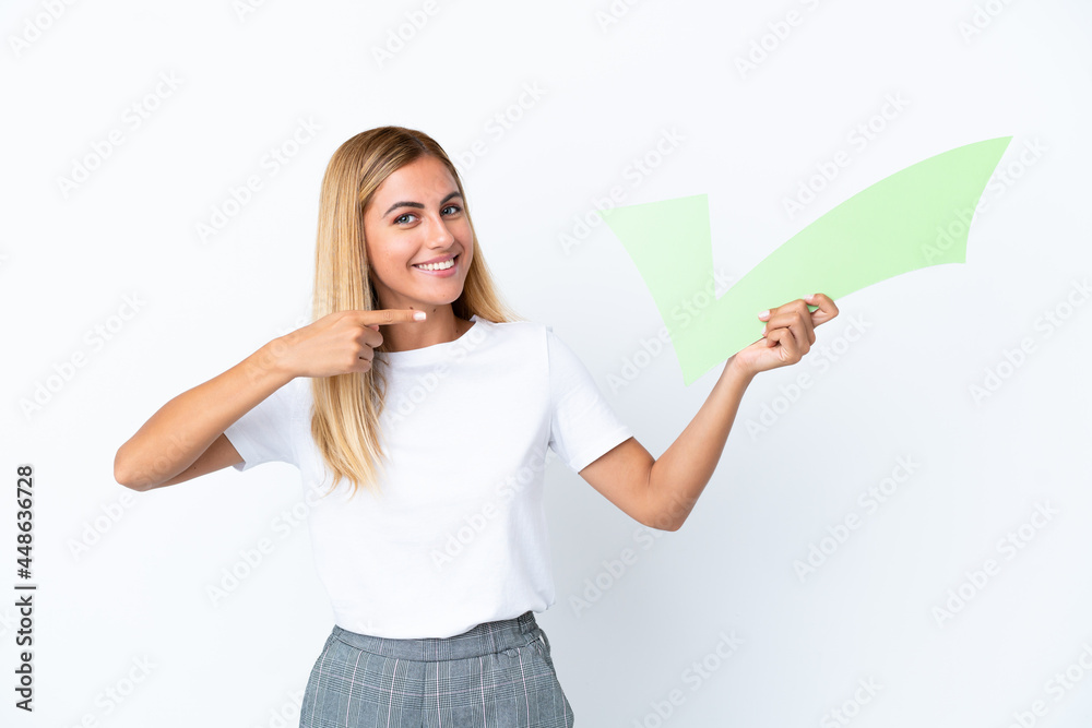Blonde Uruguayan girl isolated on white background holding a check icon and pointing it Blonde Uruguayan girl isolated on white background holding a check icon and pointing it