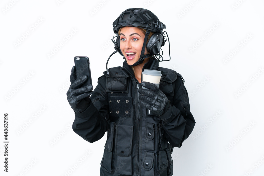 SWAT caucasian woman isolated on white background holding coffee to take away and a mobile SWAT caucasian woman isolated on white background holding coffee to take away and a mobile