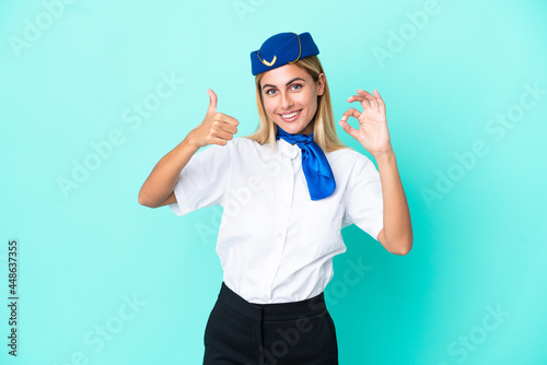 Airplane stewardess Uruguayan woman isolated on blue background showing ok sign and thumb up gesture