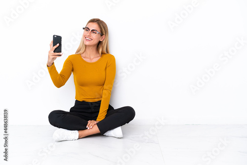Blonde Uruguayan girl sitting on the floor making a selfie