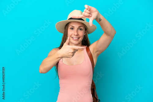 Young caucasian woman in summer holidays isolated on blue background focusing face. Framing symbol