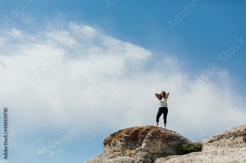a beautiful woman looks at the view on top of a cliff on a cliff on a journey