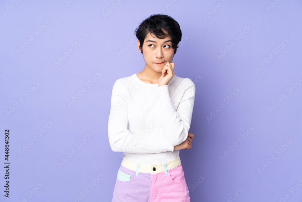 Young Vietnamese woman with short hair over isolated purple background having doubts and thinking Young Vietnamese woman with short hair over isolated purple background having doubts and thinking