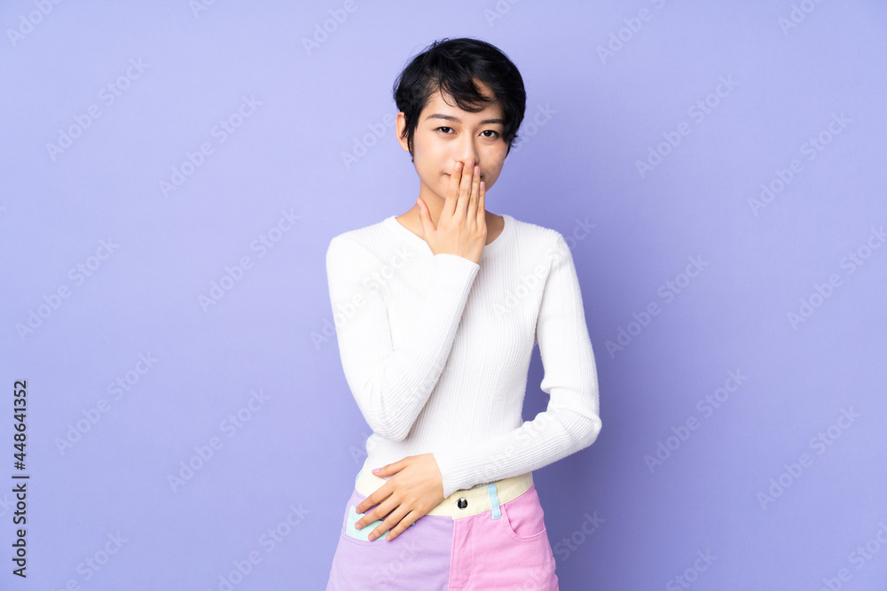 Young Vietnamese woman with short hair over isolated purple background covering mouth with hand Young Vietnamese woman with short hair over isolated purple background covering mouth with hand