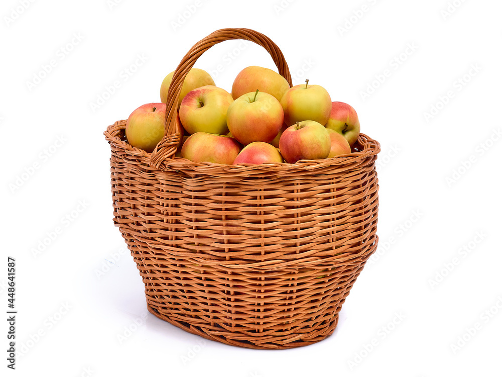 Fresh ripe yellow with red apples in a wicker basket, isolated on a white background