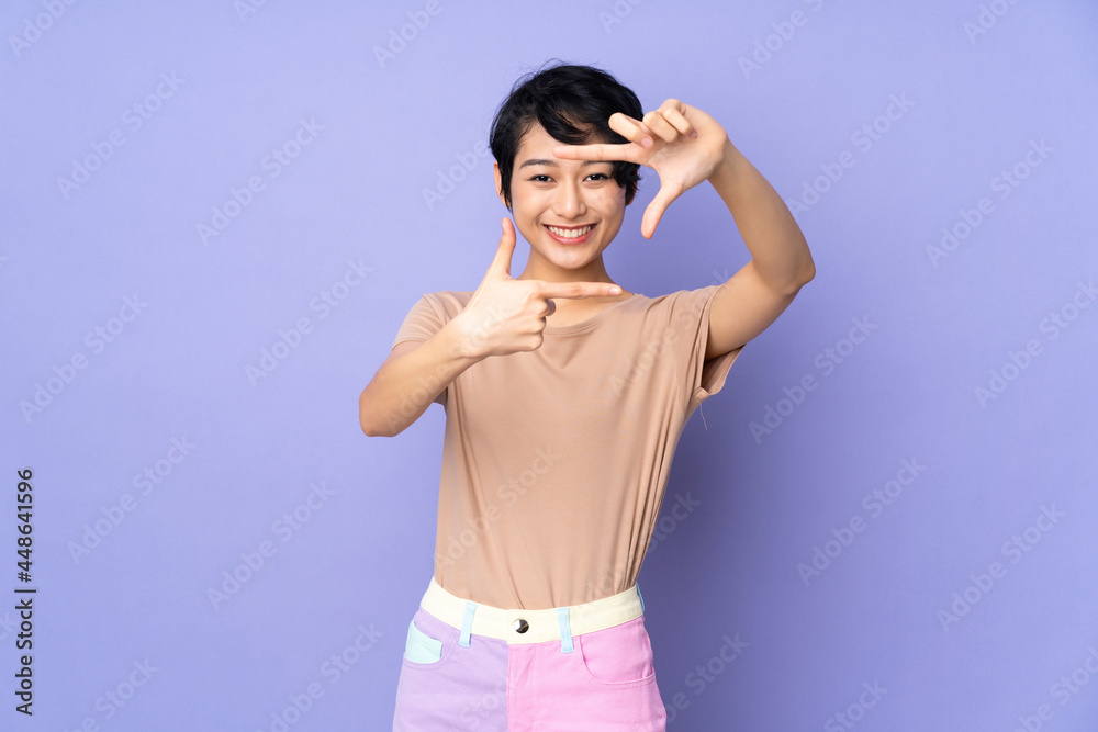 Young Vietnamese woman with short hair over isolated purple background focusing face. Framing symbol