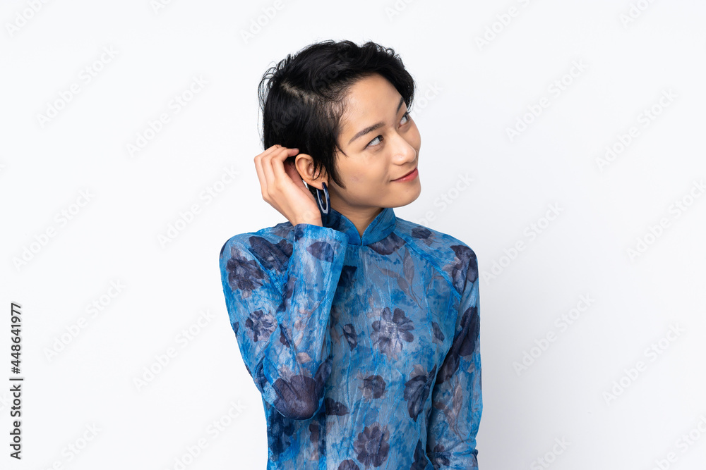 Young Vietnamese woman with short hair wearing a traditional dress over isolated white background thinking an idea Young Vietnamese woman with short hair wearing a traditional dress over isolated white background thinking an idea