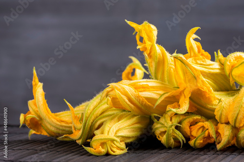 Raw zucchini flower concept  Fine dining cuisine of edible fresh and organic flowers. Healthy lifestyle ingredients. Close-up on yellow vegetables on black background with large copy space.