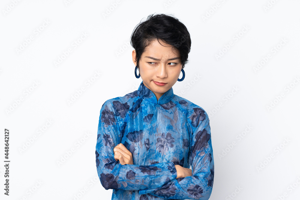 Young Vietnamese woman with short hair wearing a traditional dress over isolated white background with unhappy expression Young Vietnamese woman with short hair wearing a traditional dress over isolated white background with unhappy expression