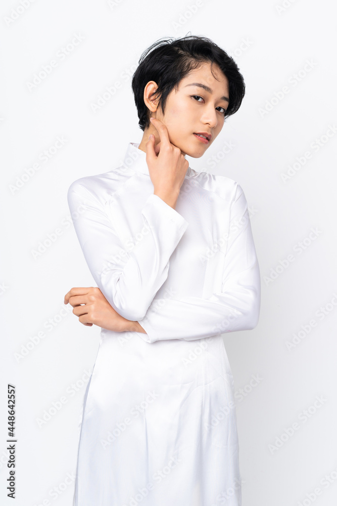Young Vietnamese woman with short hair wearing a traditional dress over isolated white background Young Vietnamese woman with short hair wearing a traditional dress over isolated white background